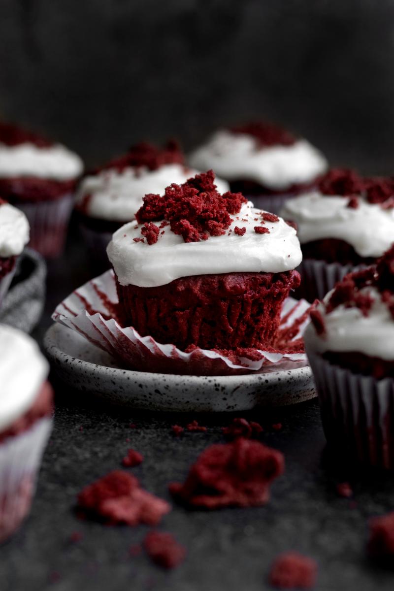 A Red Velvet Cupcake sits with the wrapper peeled down seductively.