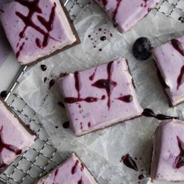 Several creamy blueberry fudge bars squares with lavender blueberry cream cheese topping.