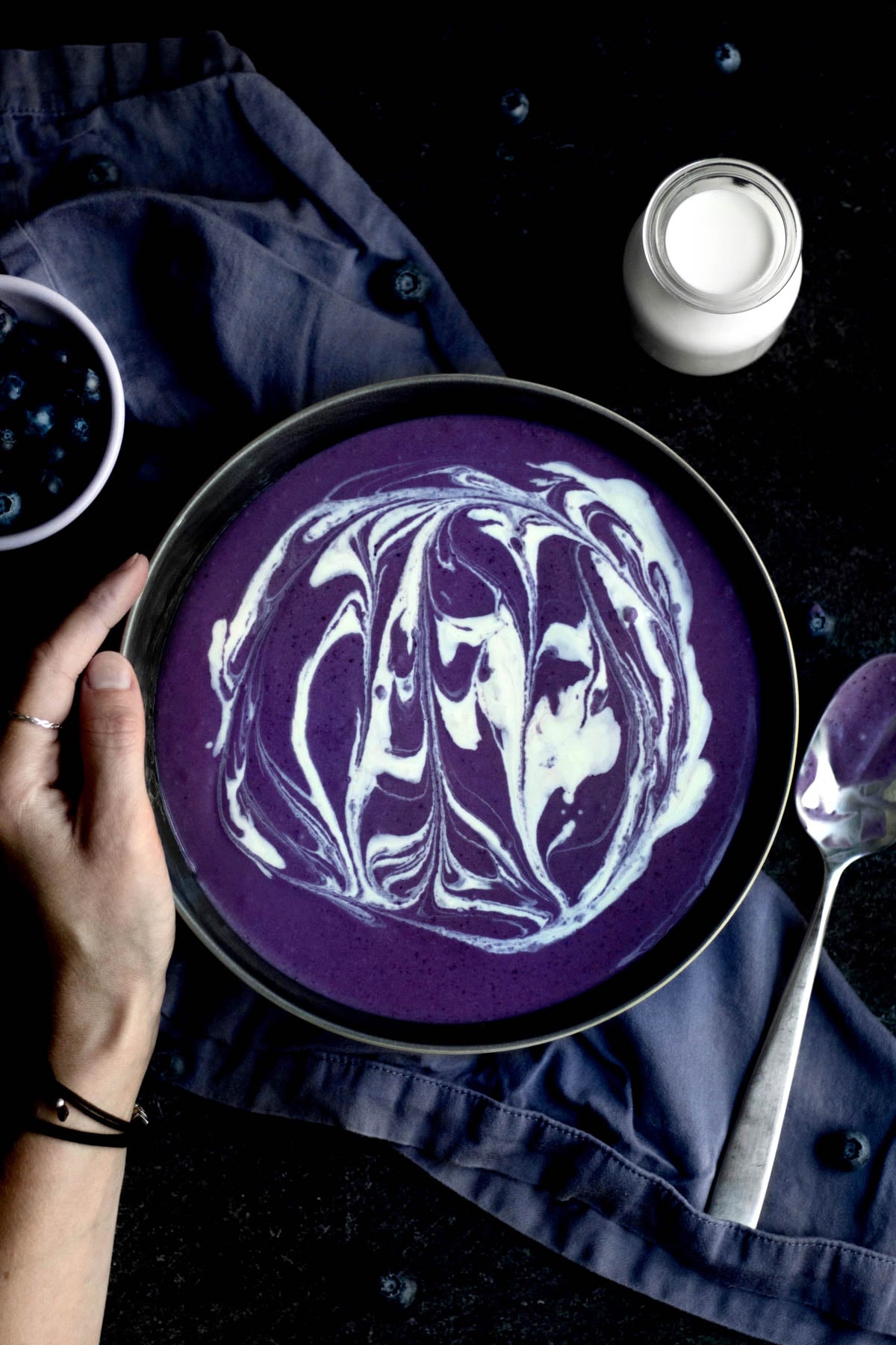 Stirring in a swirl of heavy cream into the purple blueberry liquid.