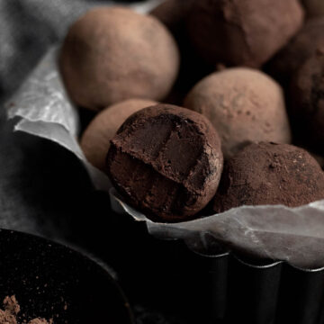 Gluten free and nut free Cocoa Dusted Truffles arranged on a plate with a bite taken out of one.