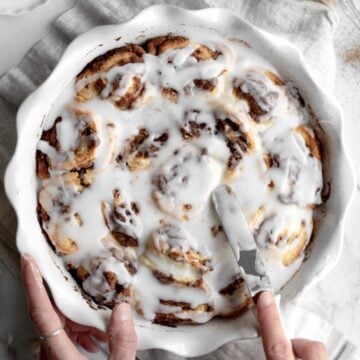 Spreading generous portions of sugary glaze onto the No Yeast Cinnamon Rolls.