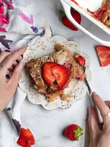 Hands using a fork on gluten free and nut free Strawberry Apple Dump Cake.