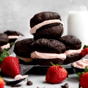 Four gluten free whoopee pies sit in a stack with strawberries.