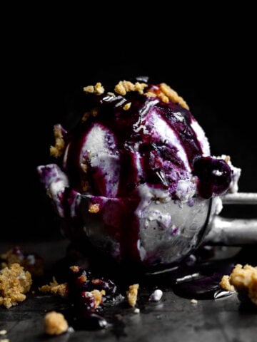 Blueberry Cheesecake Ice Cream with deep purple blueberry compote and graham crackers.