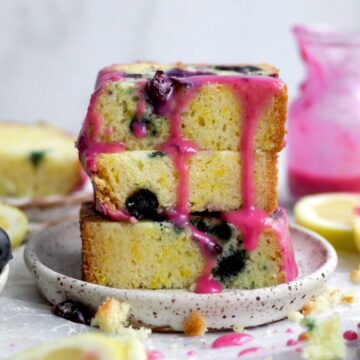 Stack of three slices of light, fluffy lemon blueberry loaf with thick blueberry glaze drip.