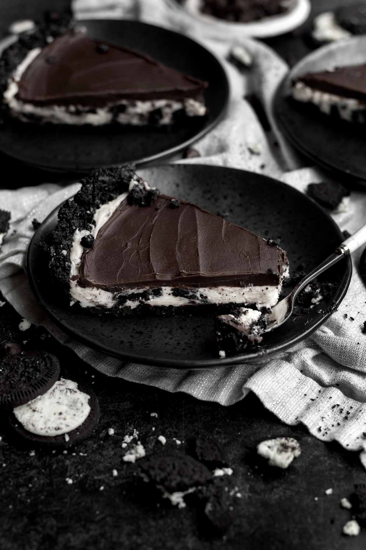 A slice of Cookies and Cream Pie on a black plate.