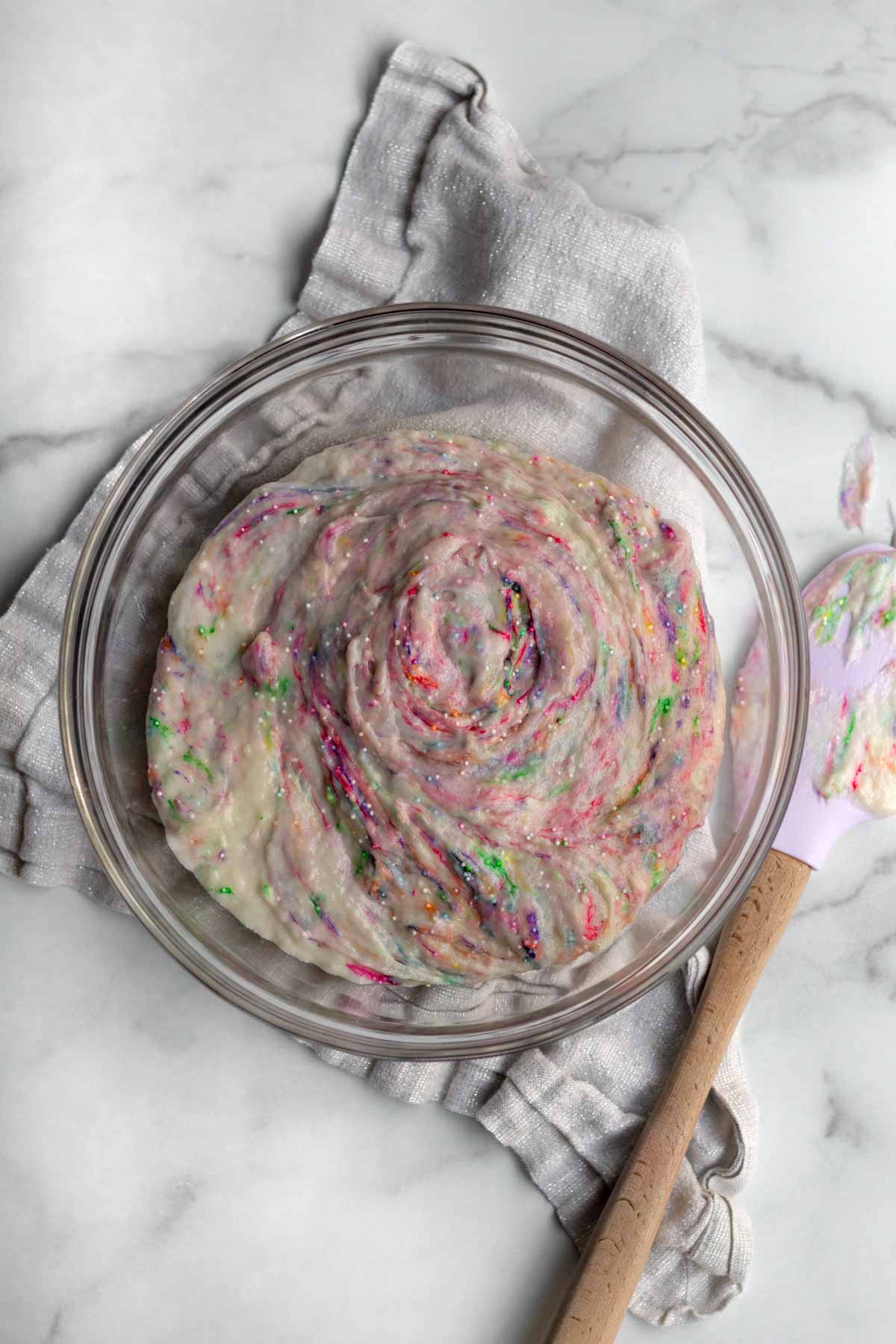 Mixing rainbow sprinkles into the donut batter.