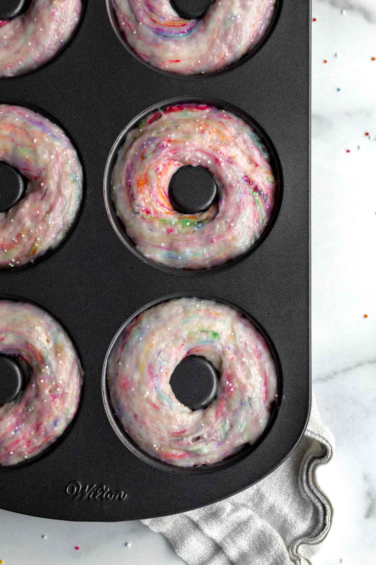 Filling the donut tray molds with the rainbow batter.