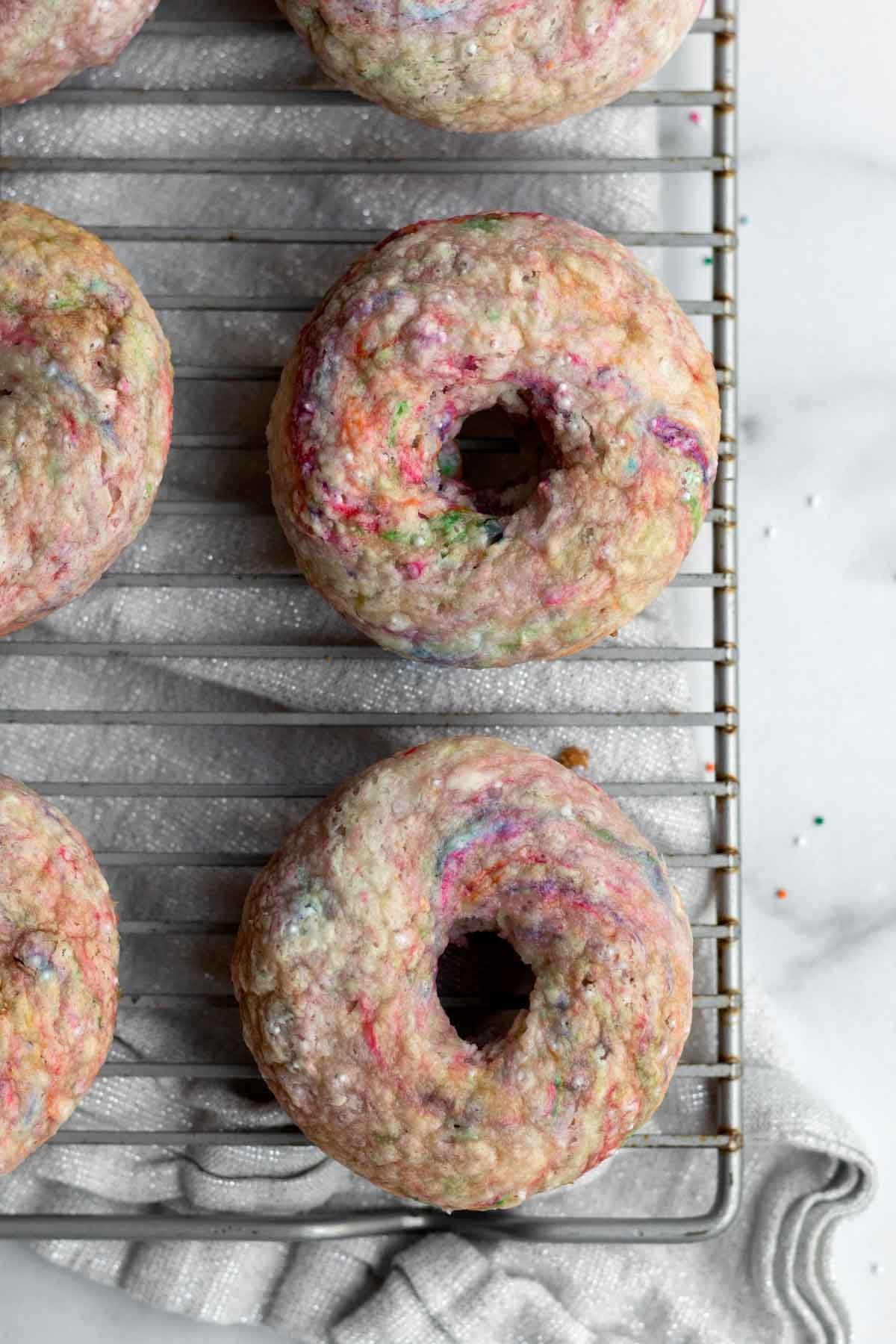 Rainbow streaked donuts on a baking rack.