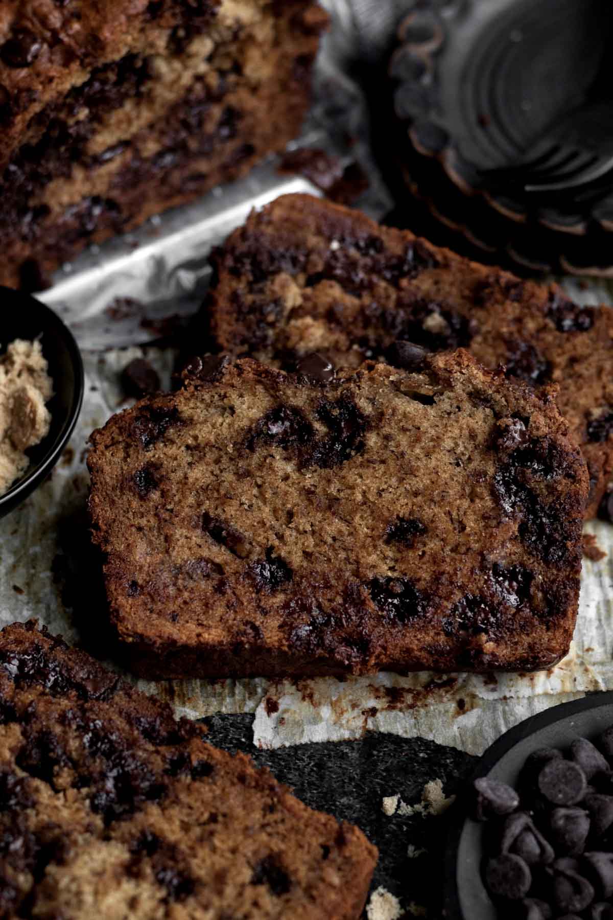 Dark punctures of chocolate perforate the banana bread slices.