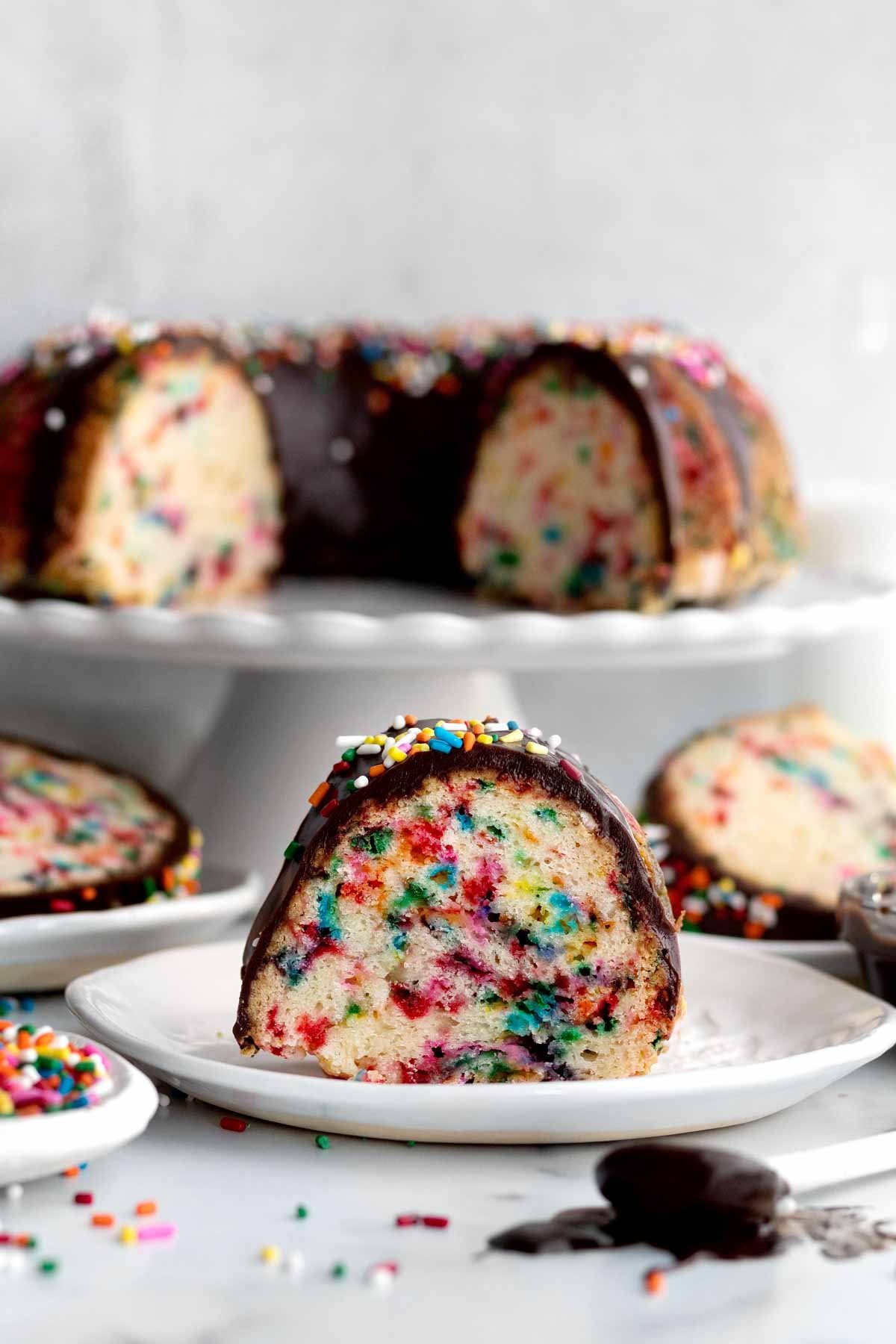 Baked rainbow sprinkles stain the insides of this bundt cake slice.