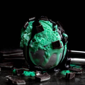 Bright green Mint Ice Cream in a scoop with dark mint chunks.