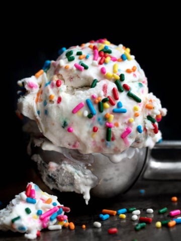 A scoop of vanilla ice cream with rainbow sprinkles in it.