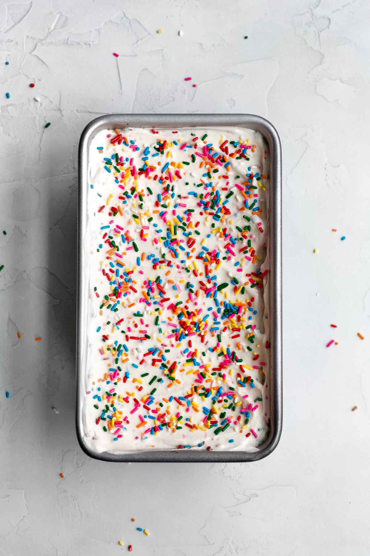 Adding extra rainbow sprinkles to the top.