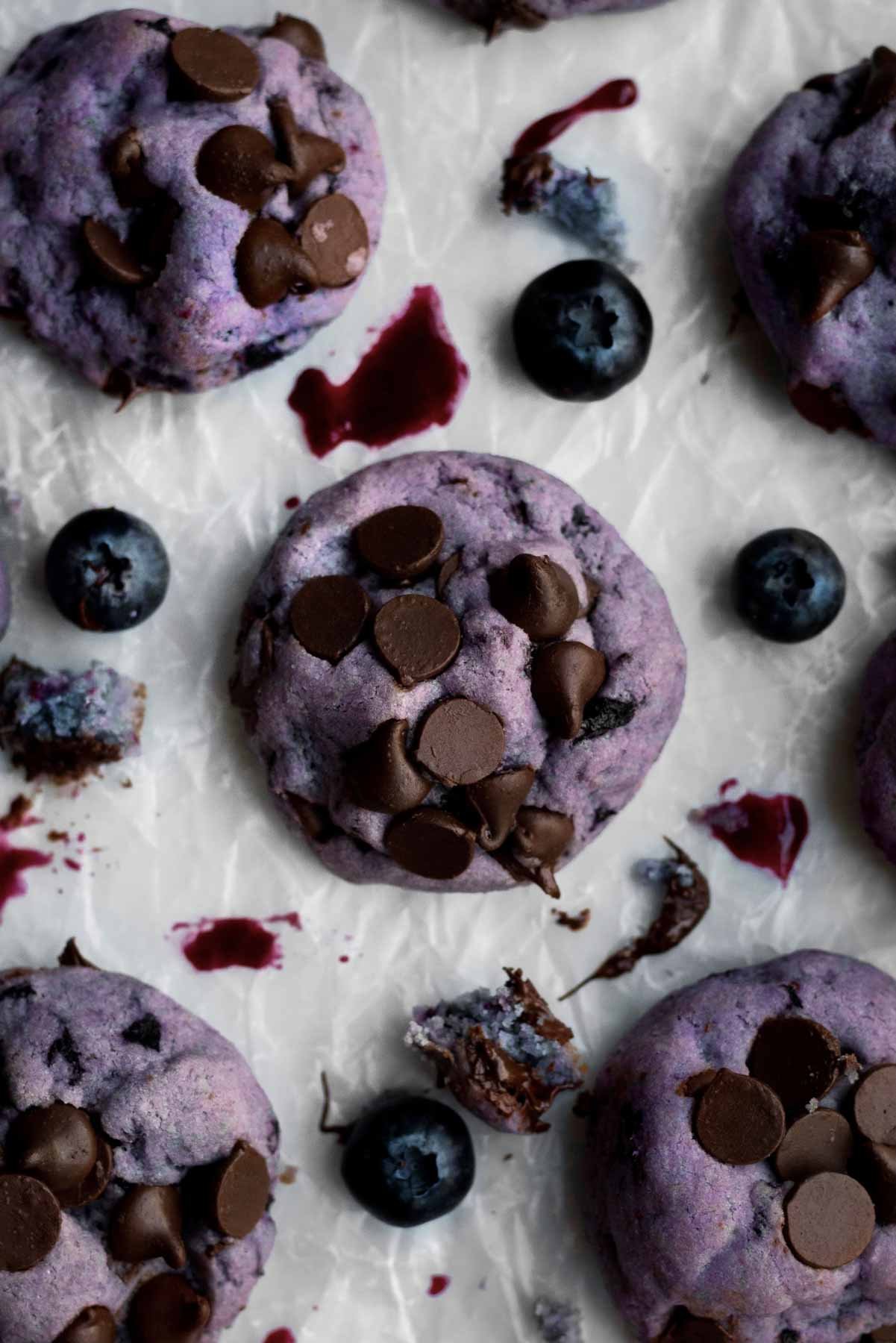Lavender Vegan Blueberry Cookies with brown chocolate chips on parchment paper.