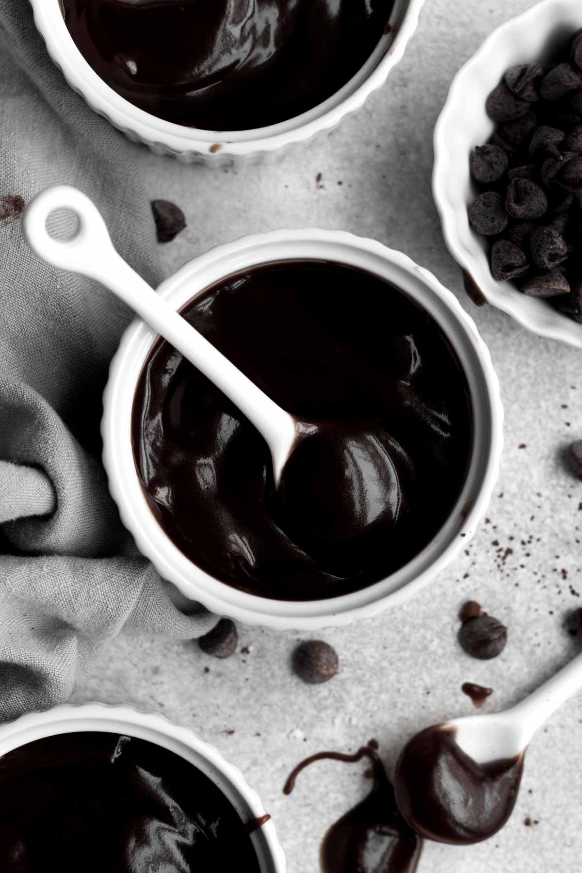 A white ceramic spoon in a ramekin of dark delicious pudding.