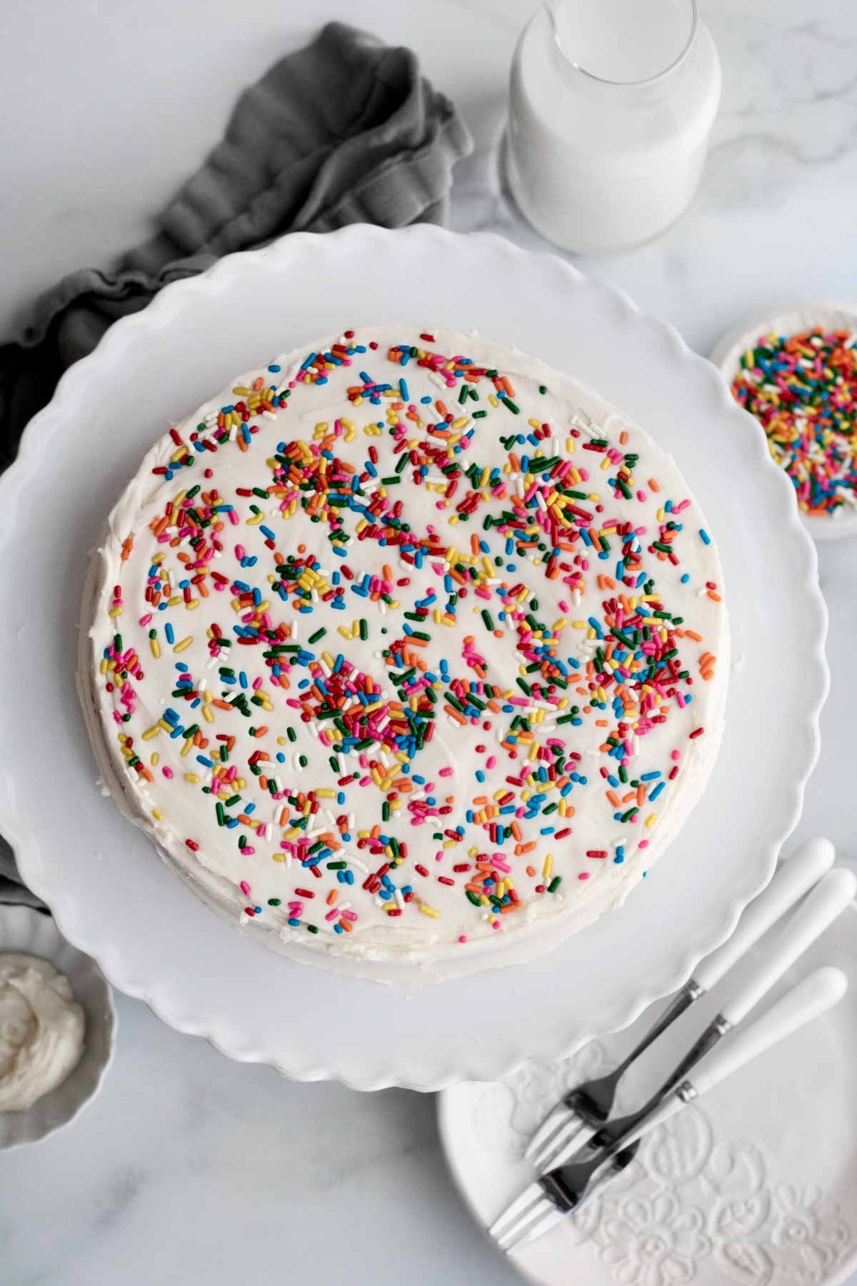 Looking down at the whole round white cake topped with sprinkles.