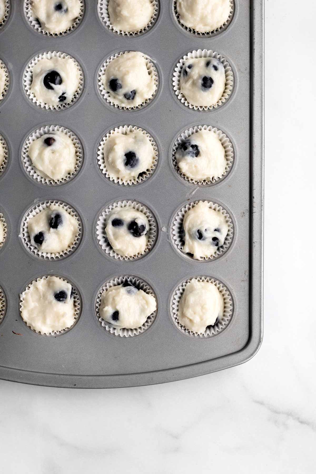 Putting the batter into muffin wrappers in a muffin tin.