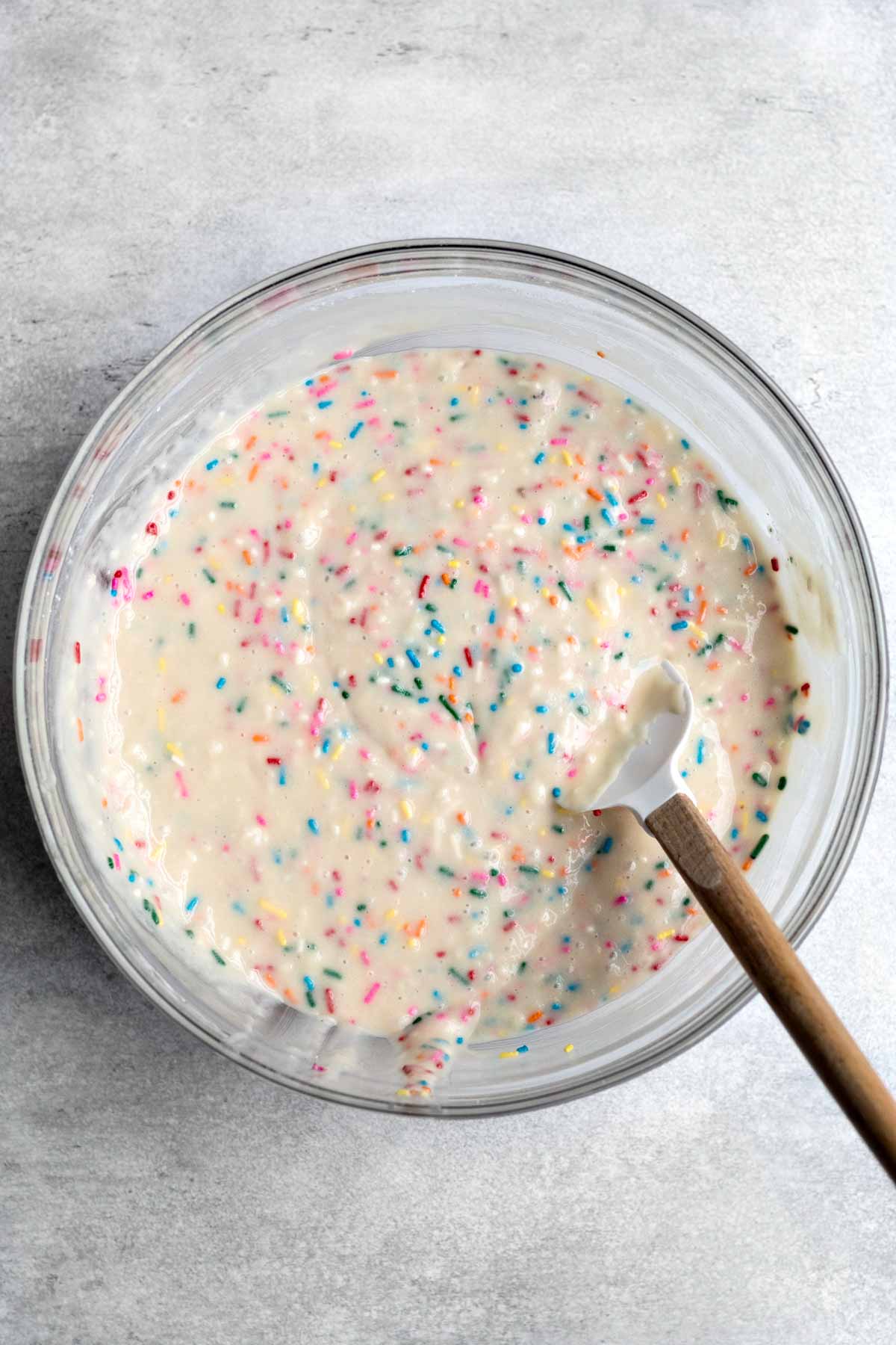 Mixing the sprinkles throughout the batter.