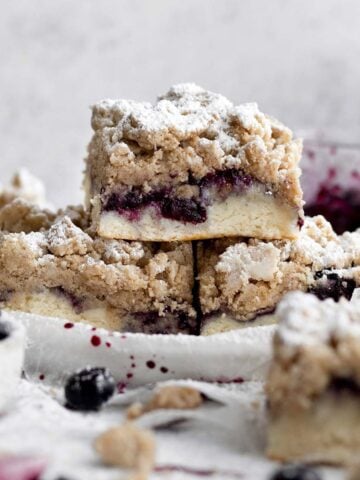 A trio of powdered Blueberry Crumb Cakes rises from the plate.