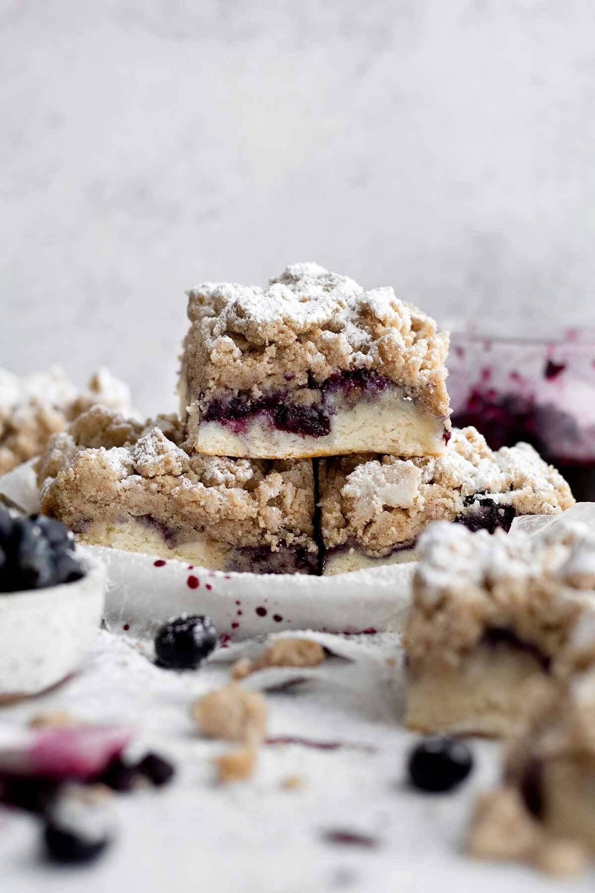 A trio of powdered Blueberry Crumb Cakes rises from the plate.