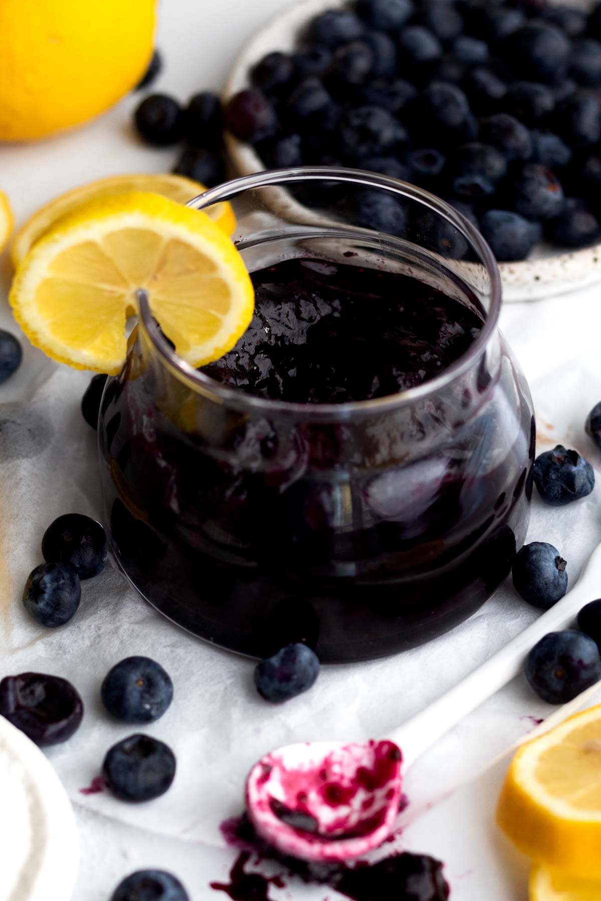 A glass ramekin with blueberry jam.