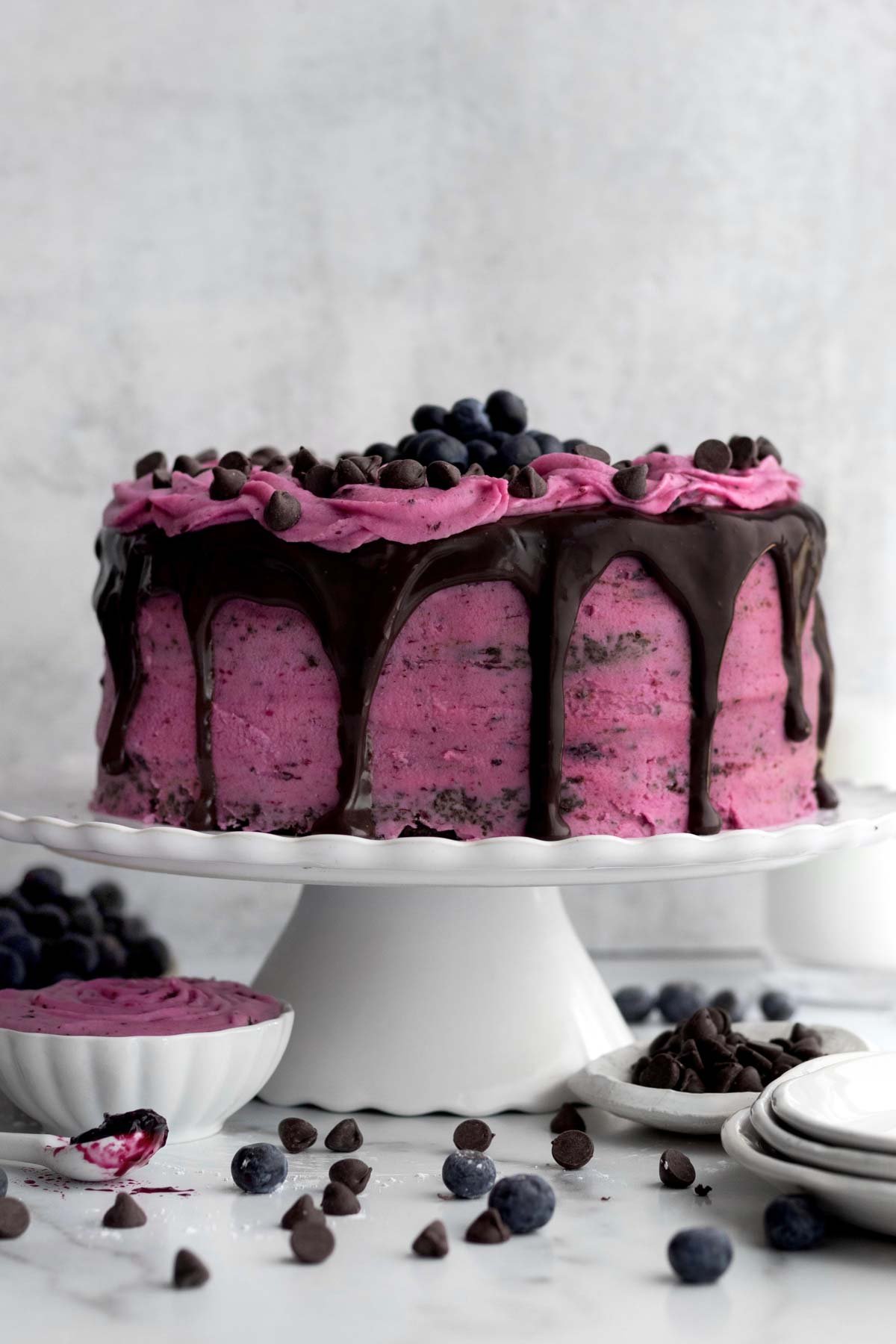 A cake with Blueberry Frosting dripping in chocolate ganache.
