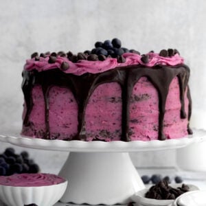 A complete Chocolate Blueberry Cake dripping with chocolate ganache topped with blueberries.