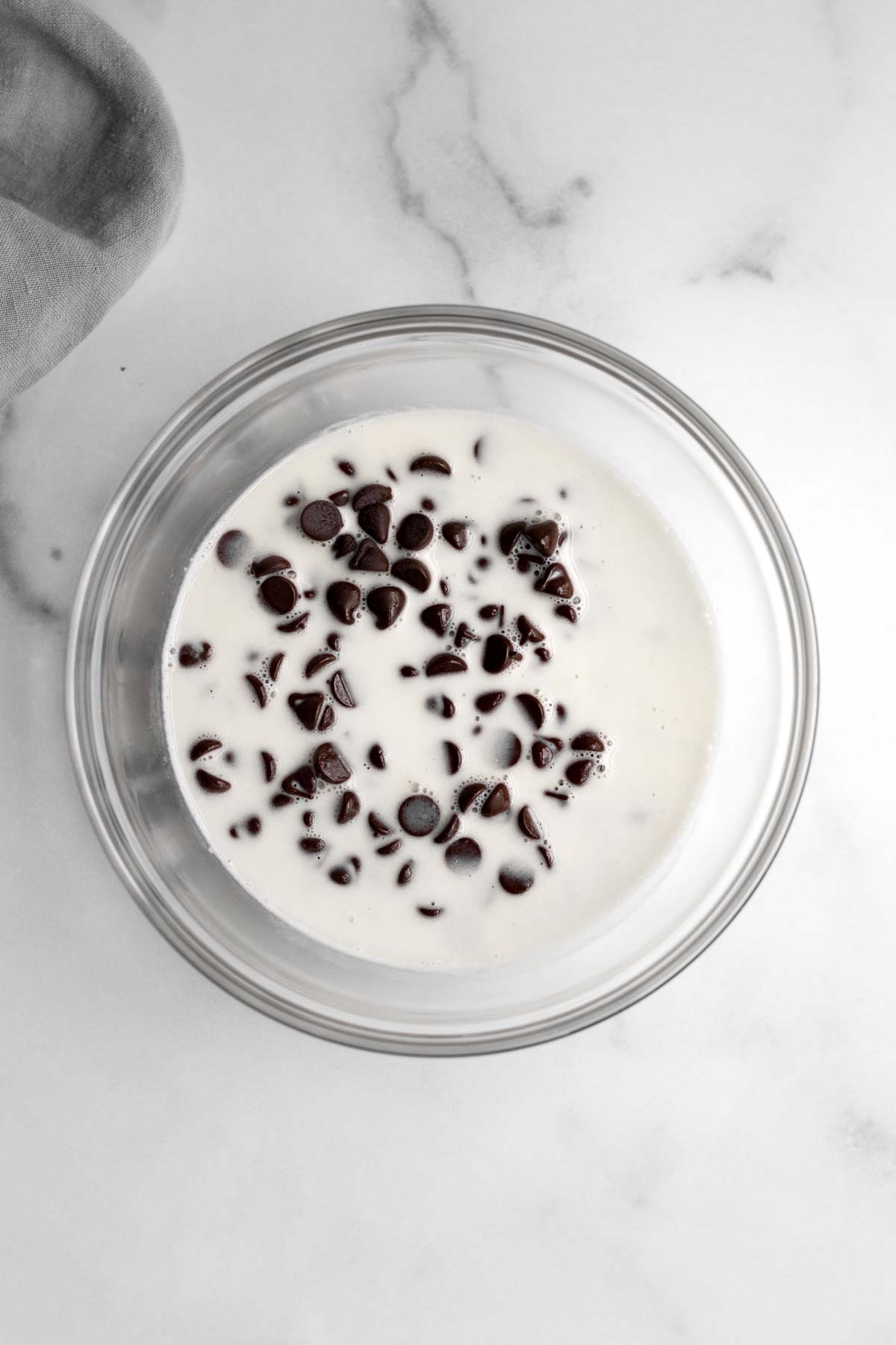 A glass bowl with milk and chocolate chips.
