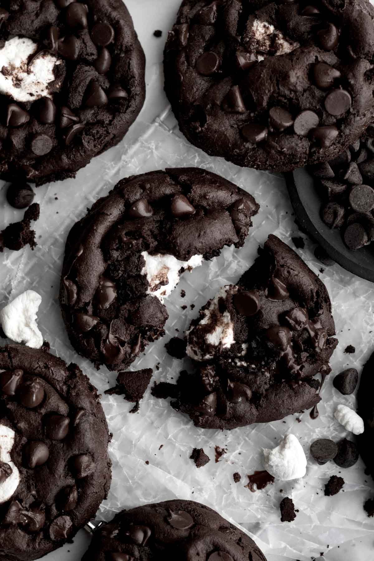 Chocolate Marshmallow cookies on parchment paper with one torn in half.