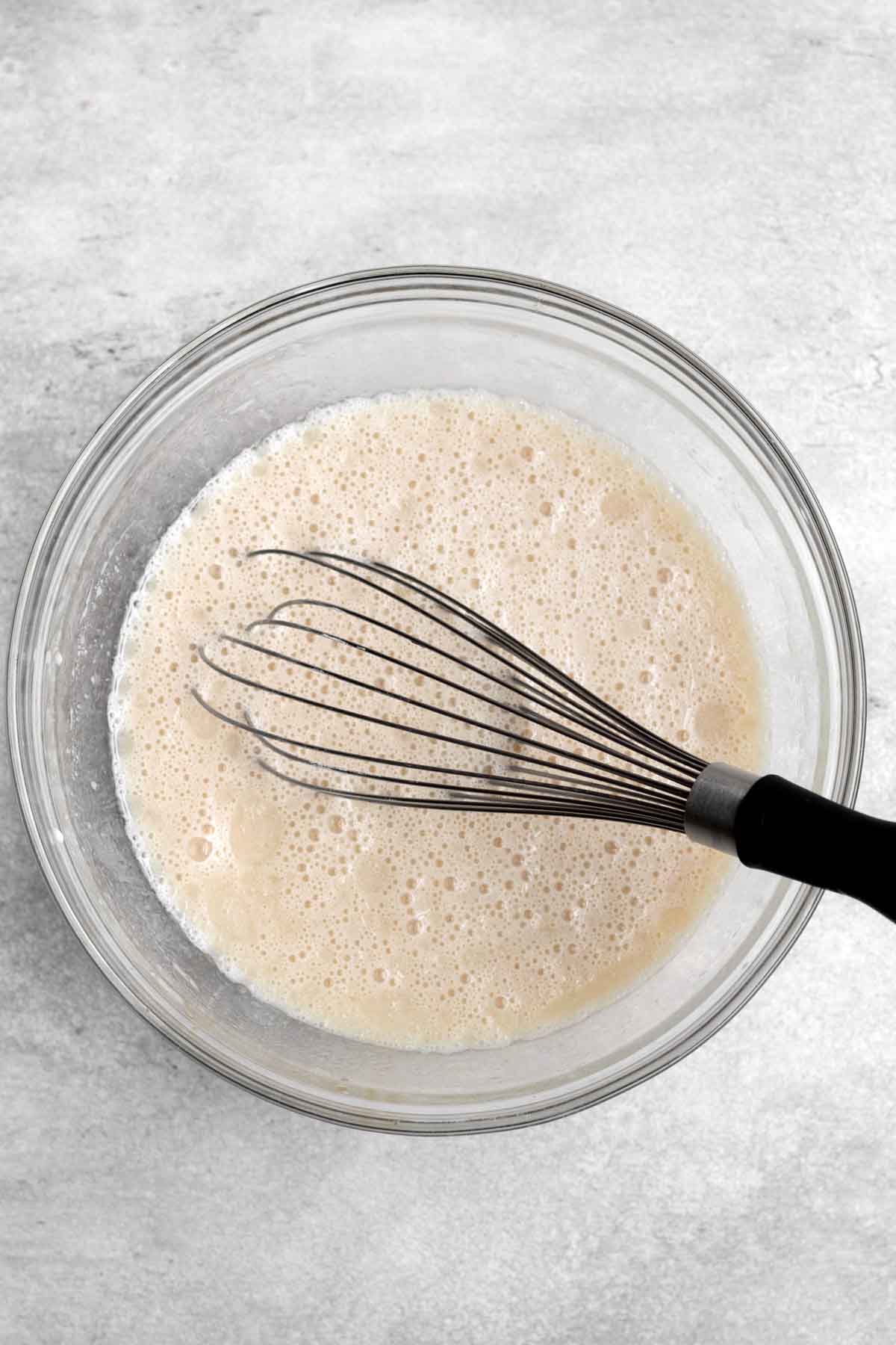 A whisk in the wet.ingredients in a bowl/