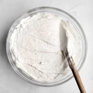 A spatula stirs the delicious frosting smooth.