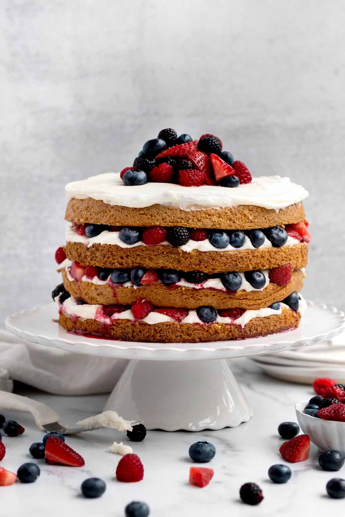 A layer cake with berries and vanilla frosting.