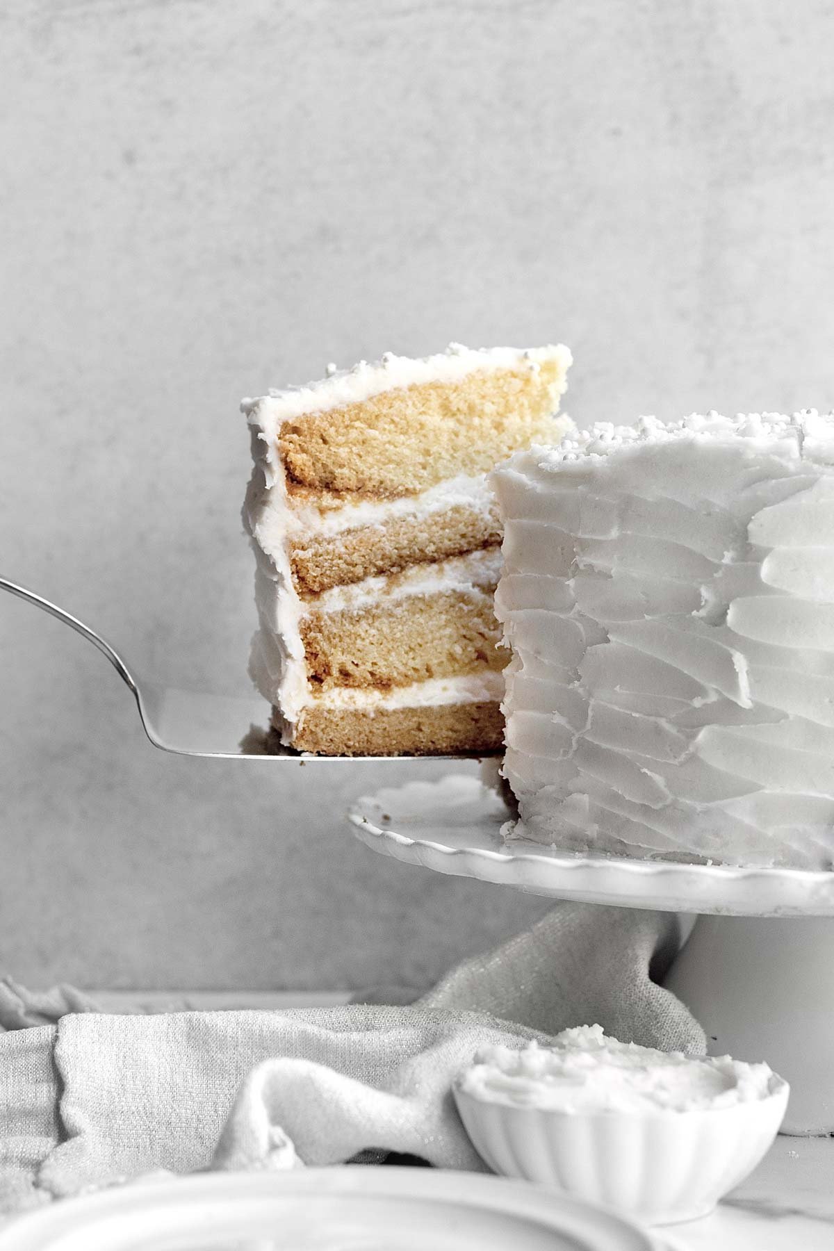 A vanilla frosted cake slice is taken from the whole.