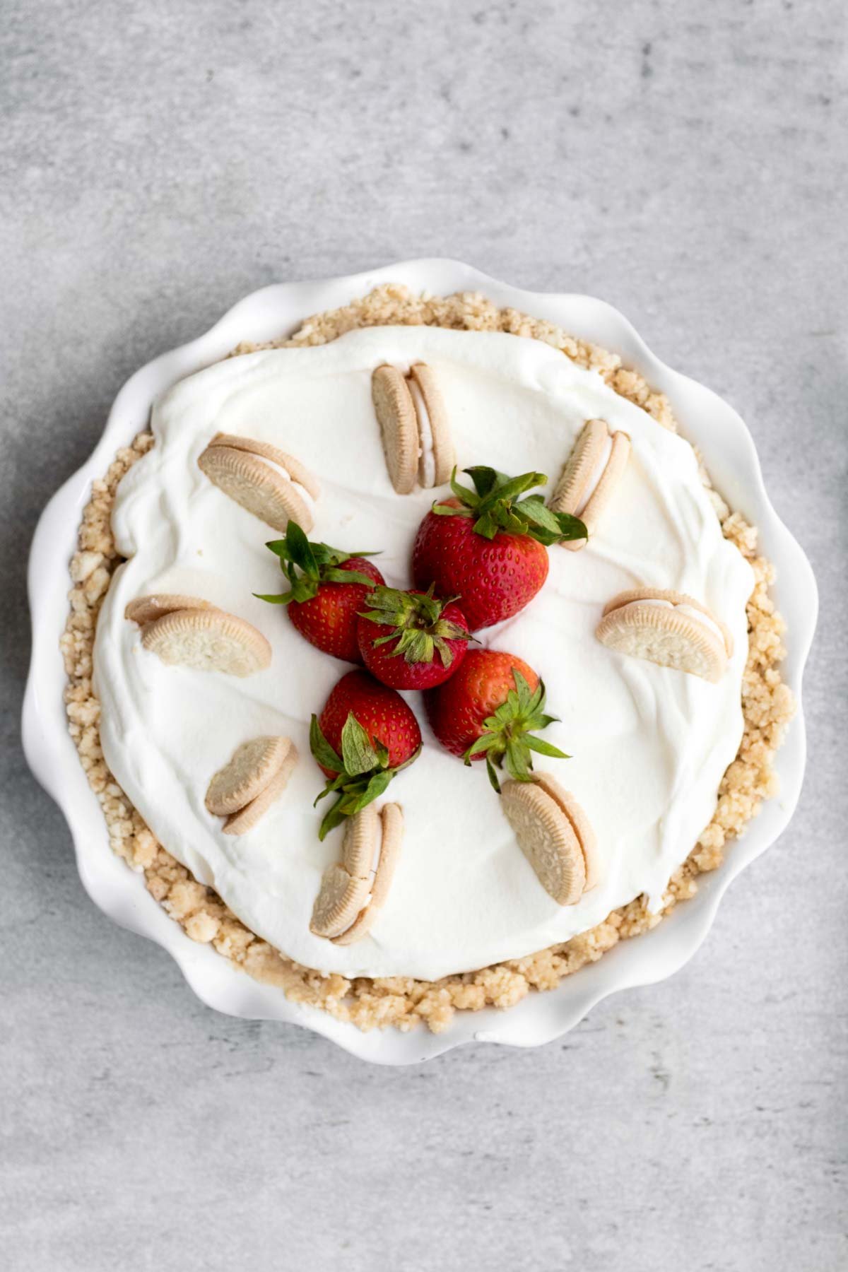 A pie topped with golden sandwich cookies and strawberries.