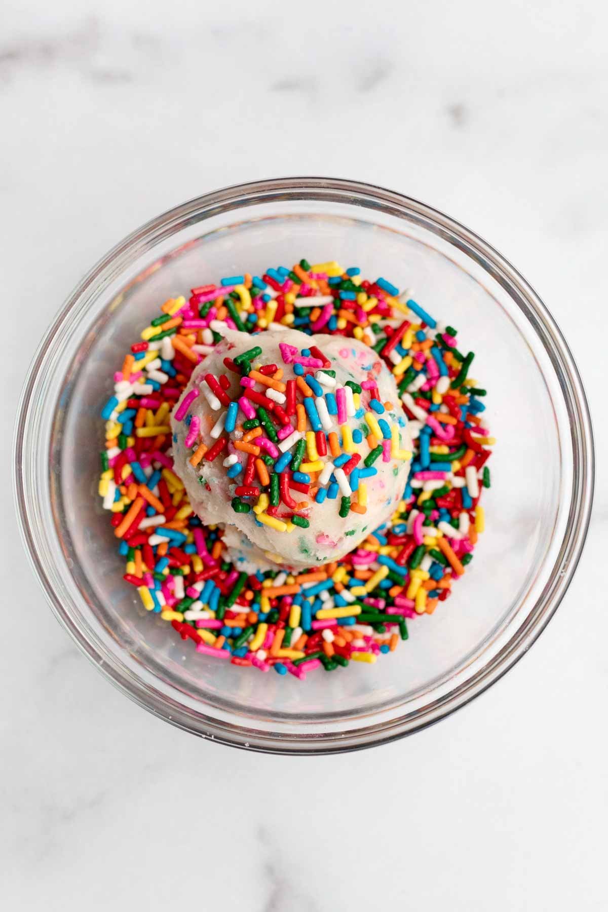 A ball of dough in a bowl with rainbow sprinkles.