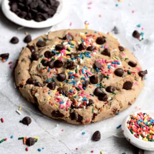 A giant Happy Birthday Cookie with rainbow sprinkles and chocolate chips.