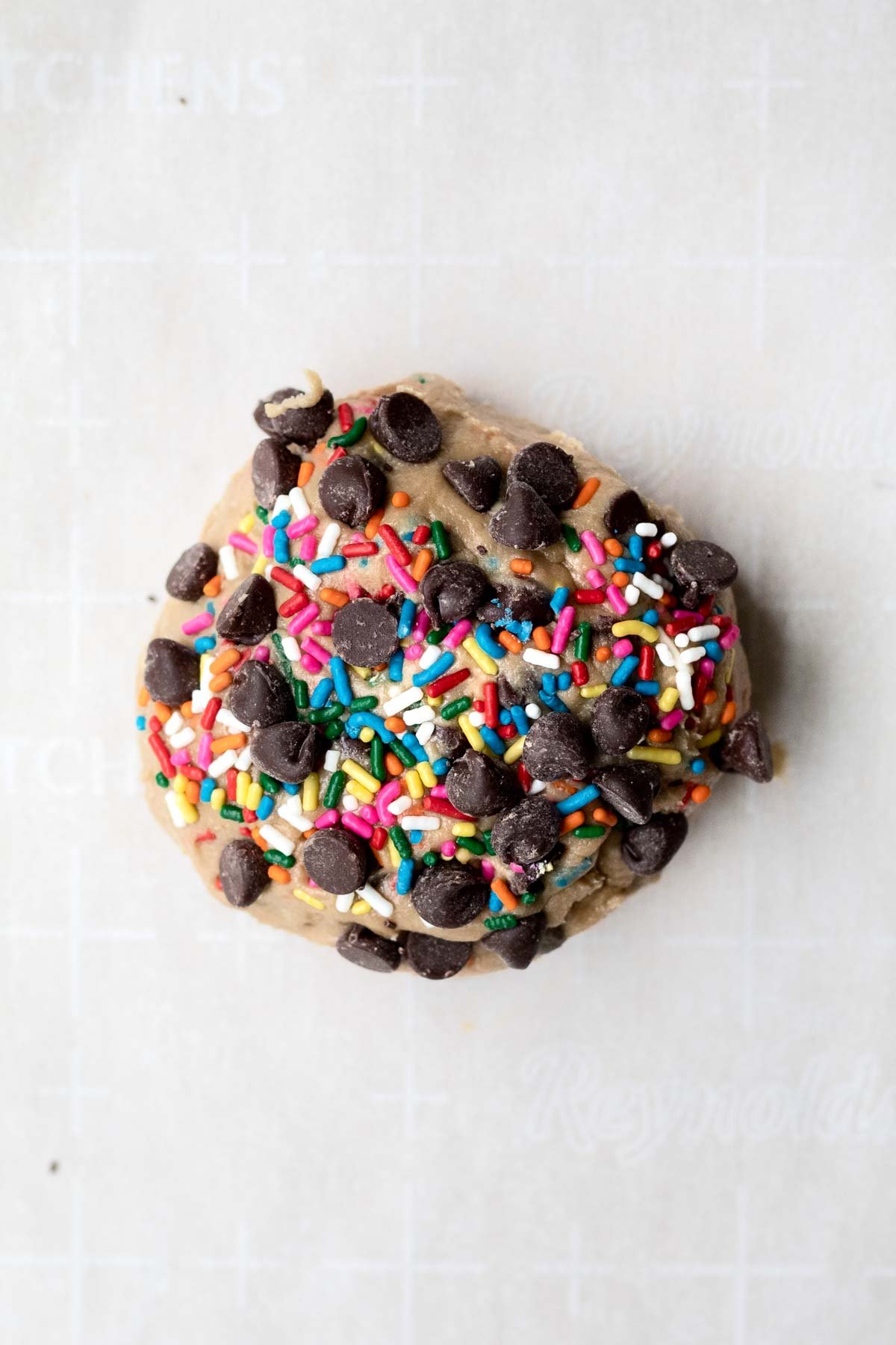 Adding more chocolate chips and rainbow sprinkles to the top.