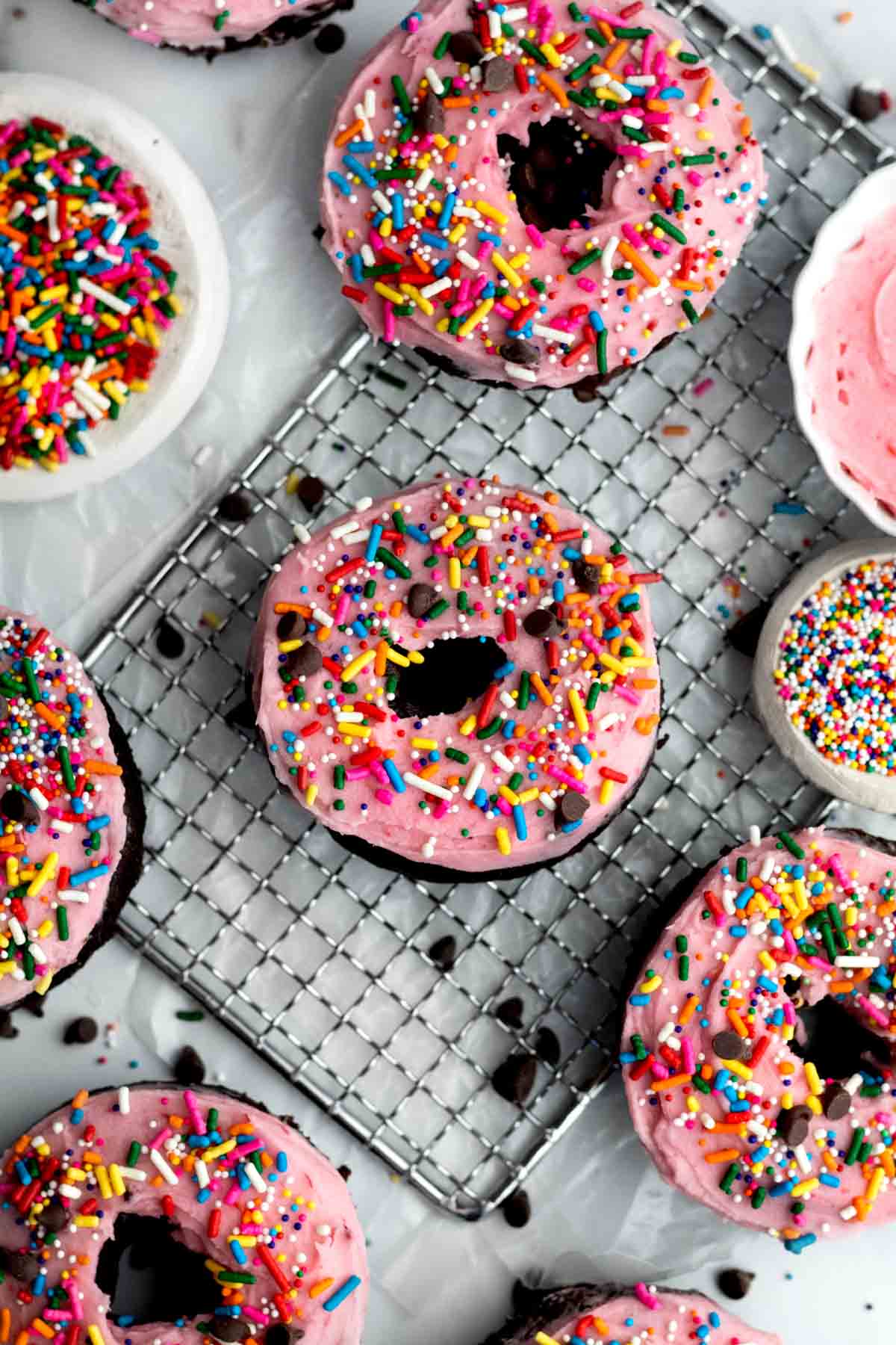 Looking down at pink raspberry frosted donuts with rainbow sprinkles.