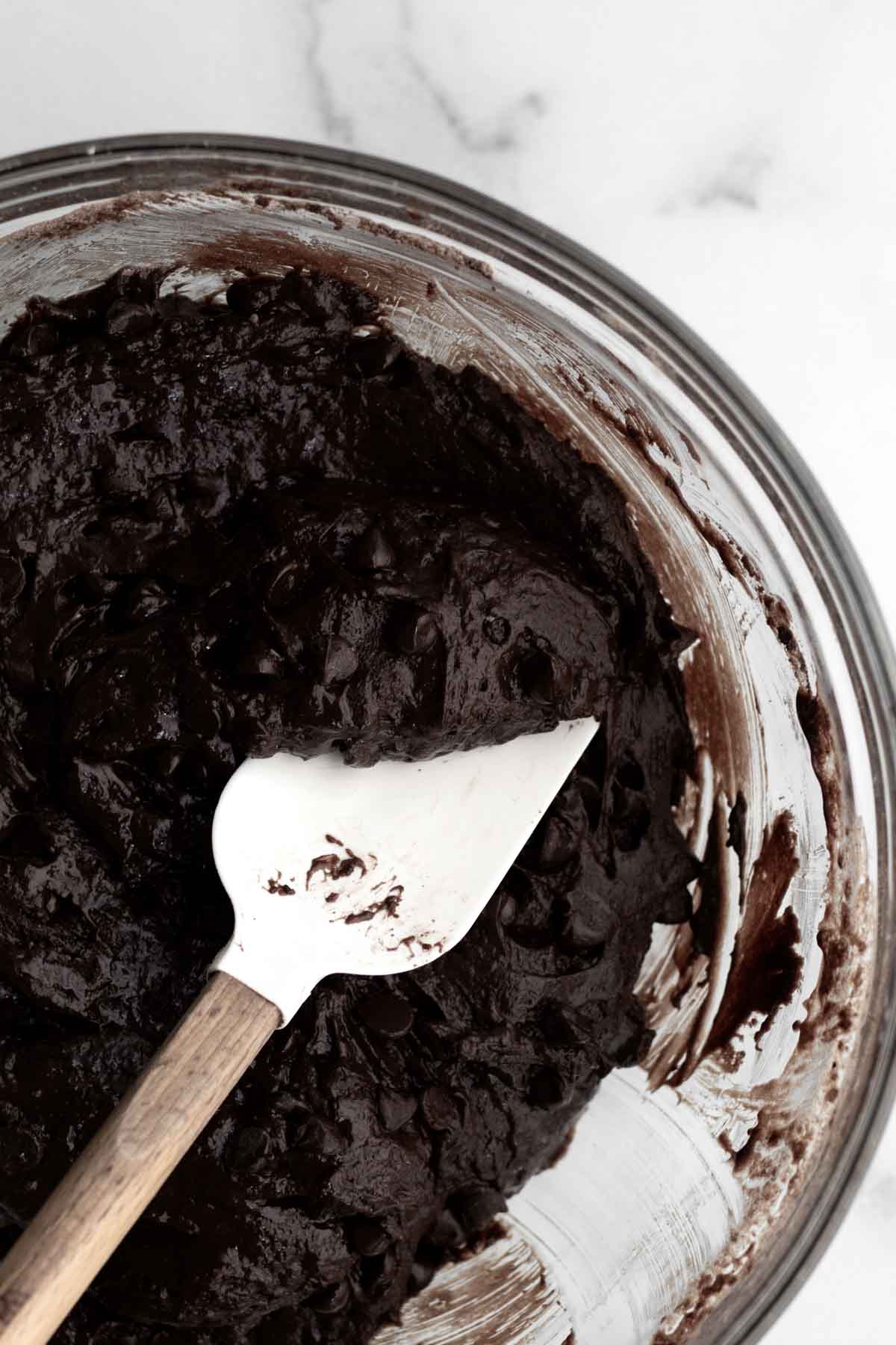 Dark chocolate donut batter with chocolate chips mixed in.