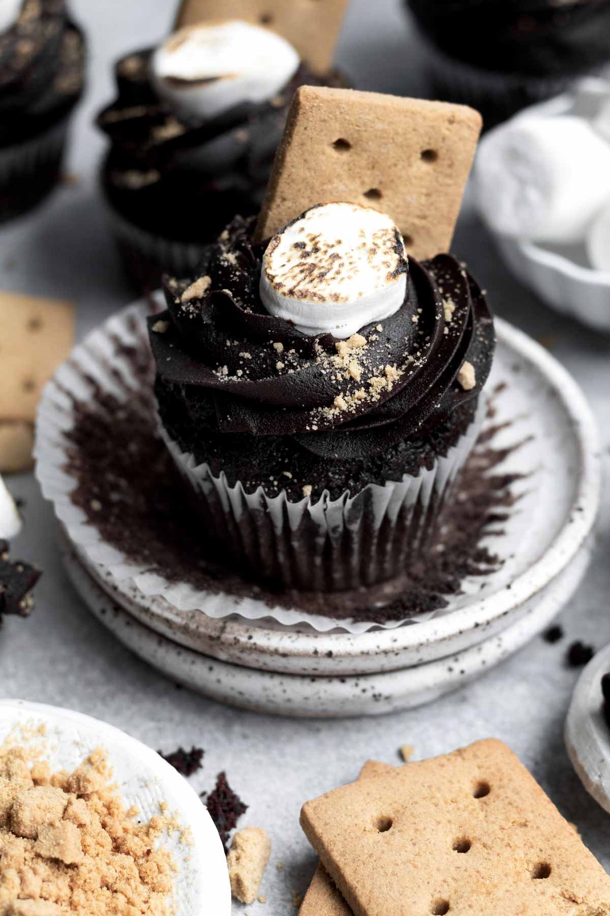 Gluten free Marshmallow Cupcakes sit amongst plates of marshmallow and graham crackers.