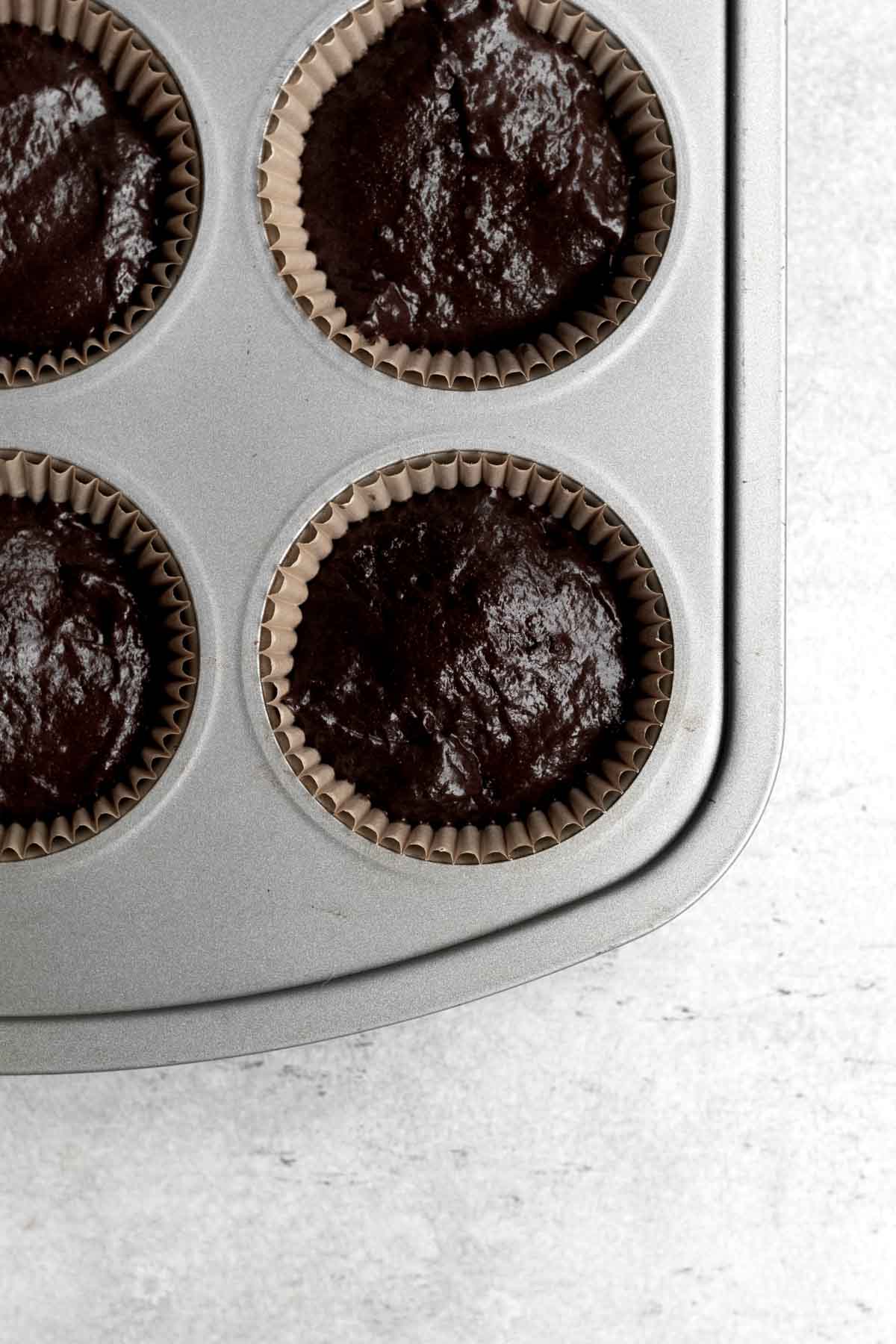 Chocolate cupcake batter in a cupcake tin.