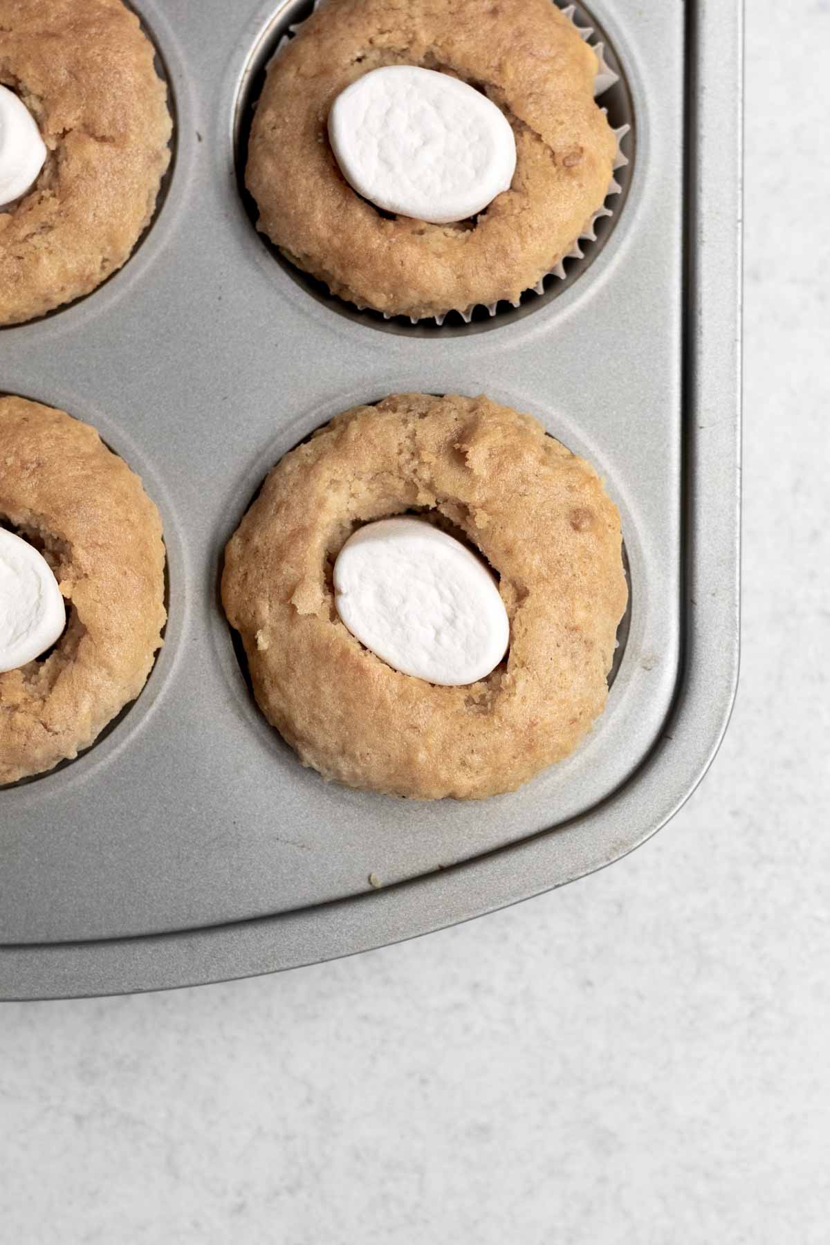 Putting one marshmallow in the cupcake hole.