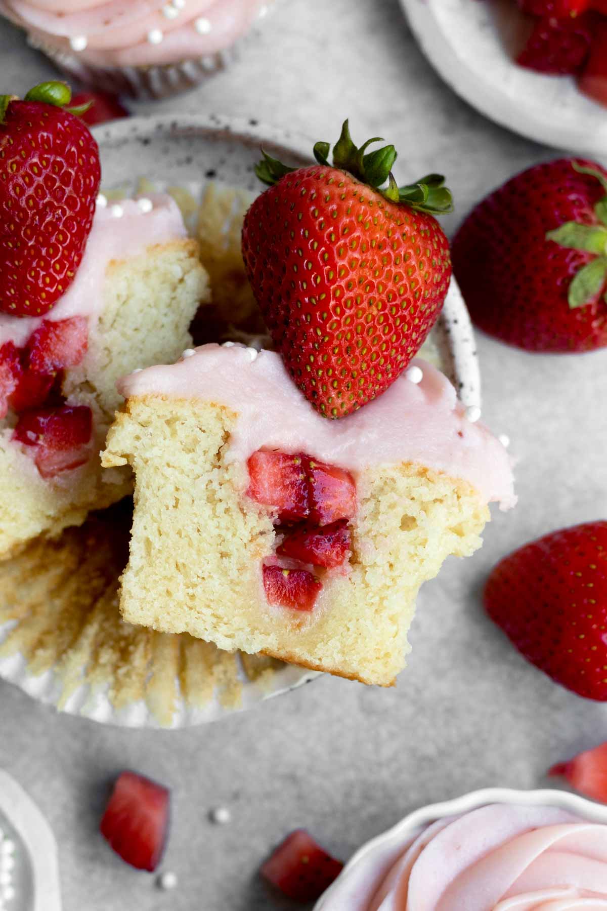 Looking down at a halved fluffy cupcake with strawberry center.
