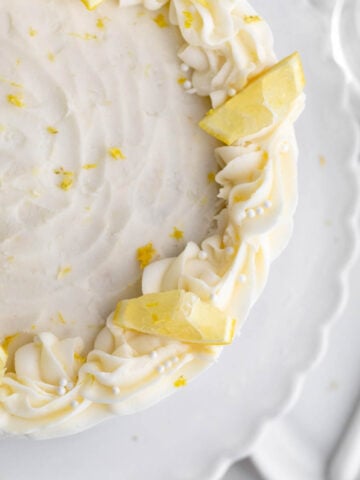 A Lemon Buttercream Frosting decorated cake with slices of lemon.