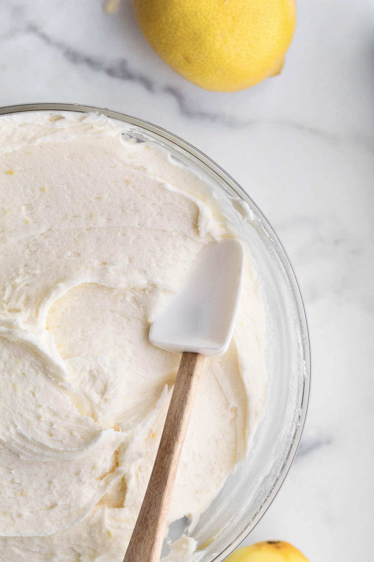 A bowl of delicious Lemon Buttercream Frosting with a spatula.