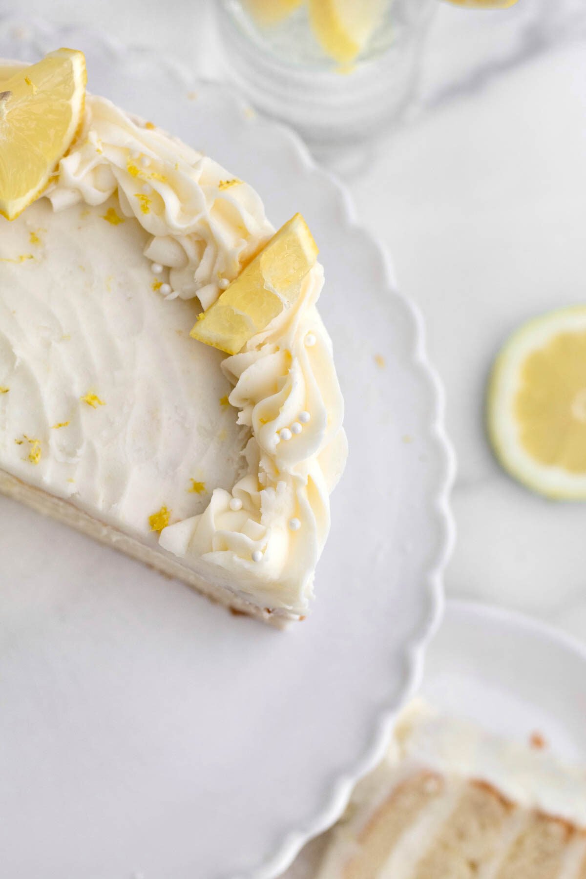 Cake with slices of lemon and frosting on a cake stand.