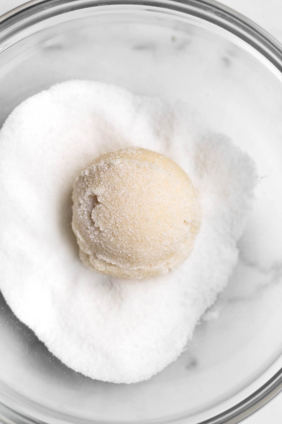 Dough balls in a bowl of granulated sugar.