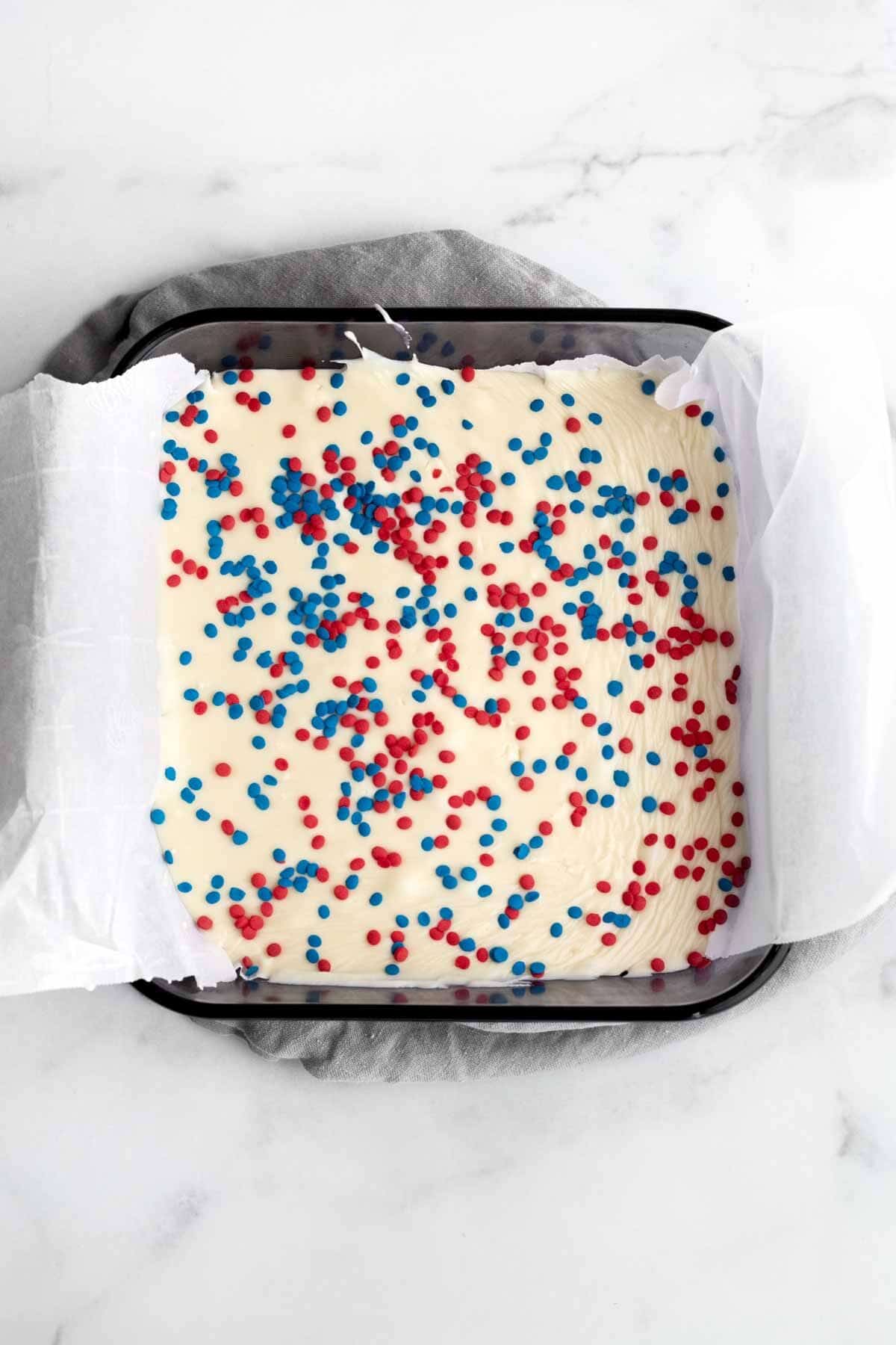 Poured fudge in a pan with red and blue sprinkles.