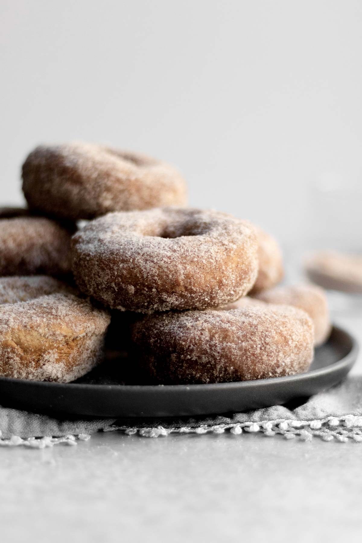 A plate of donuts sit covered in cinnamon sugar.